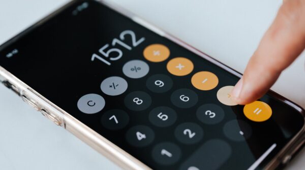 crop anonymous accountant using calculator app on smartphone