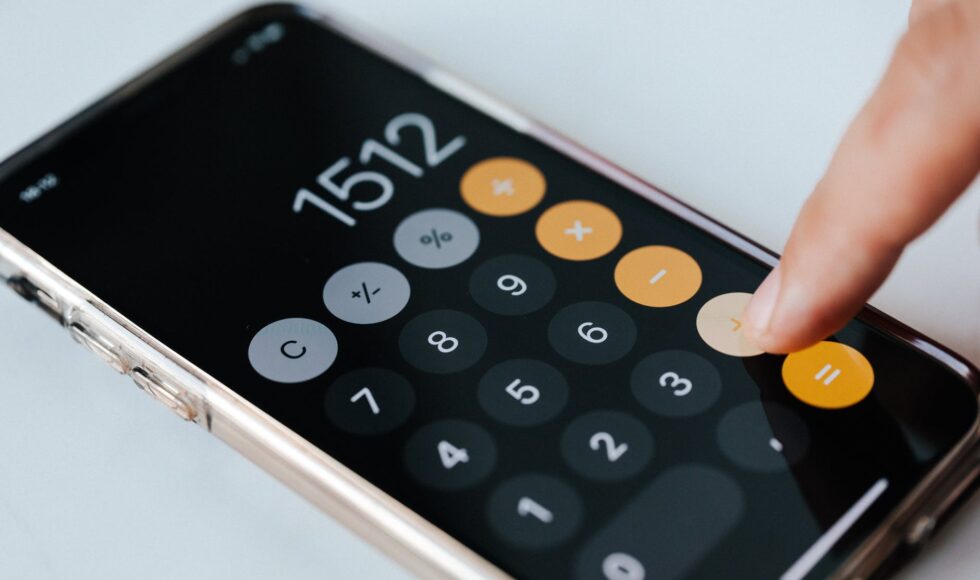 crop anonymous accountant using calculator app on smartphone
